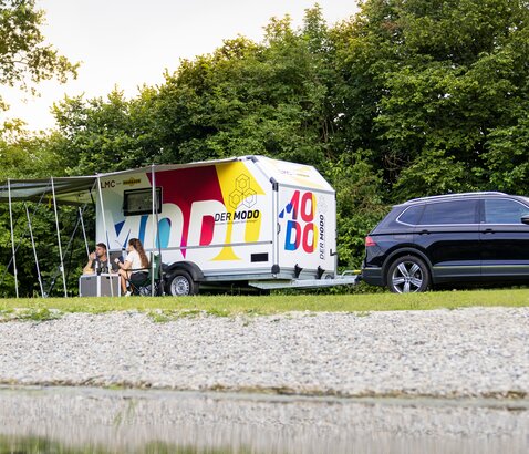 Humbaur MODO Camping | © Humbaur GmbH Campinganhänger MODO mit Campingzubehör steht auf Wiese am See. | © Humbaur GmbH