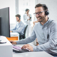 L'employé travaille sur un ordinateur avec un casque et sourit | © Humbaur GmbH